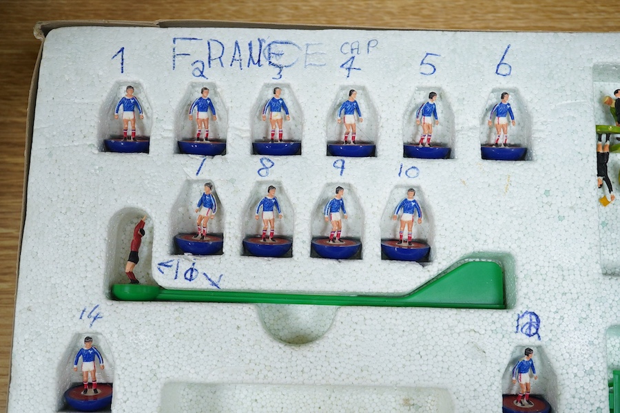 Two boxed Subbuteo table football sets; a European Edition, comprising of two teams, spectators and line side staff, pitch, etc. (some parts missing), and an International Edition, comprising of three teams, stadium ligh